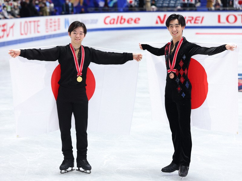 男子の表彰式後に日の丸を背にする優勝した鍵山優真（左）と壷井達也＝国立代々木競技場で2024年11月9日、猪飼健史撮影