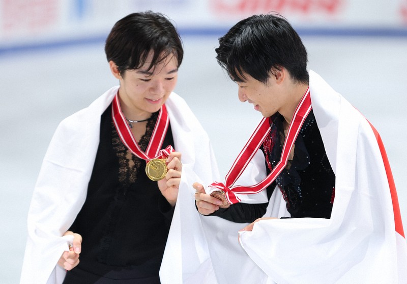 表彰式後の記念撮影でメダルを確認する鍵山優真（左）と壷井達也＝国立代々木競技場で2024年11月9日、猪飼健史撮影