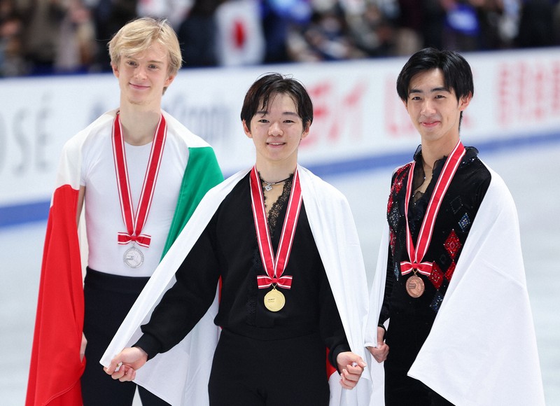 表彰式後に記念撮影する（左から）2位でイタリアのダニエル・グラスル、1位の鍵山優真、3位の壷井達也＝国立代々木競技場で2024年11月9日、猪飼健史撮影