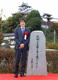 Japanese comedian Junior Chihara stands beside a monument featuring his haiku, in Fukuchiyama, Kyoto Prefecture, on Nov. 18, 2024. (Mainichi/Manabu Niwata)