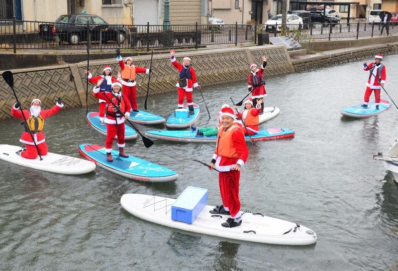 水上からメリークリスマス 「SUPサンタ」がプレゼントお届け | 毎日新聞