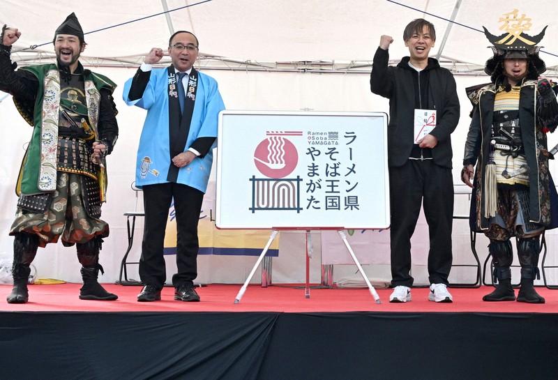 発表された「ラーメン県そば王国」のロゴマーク（中央）。右から2人目は考案した「アスタリスクデザイン」の武田容昌代表＝山形市で2024年12月7日、竹内幹撮影