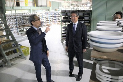 萬古陶磁器工業協同組合の熊本哲弥理事長（左）から説明を受ける山中晋一大使＝三重県四日市市三ツ谷町の銀峯陶器で2024年12月12日、原諒馬撮影