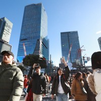高層ビルが建ち並ぶ渋谷駅前でスマートフォンを掲げながら歩く人たち＝東京都渋谷区で2024年12月23日、小出洋平撮影