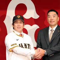 巨人の入団記者会見でユニホームに袖を通し、フォトセッションに臨む甲斐拓也（左）と阿部慎之助監督＝東京都千代田区で2024年12月26日、幾島健太郎撮影
