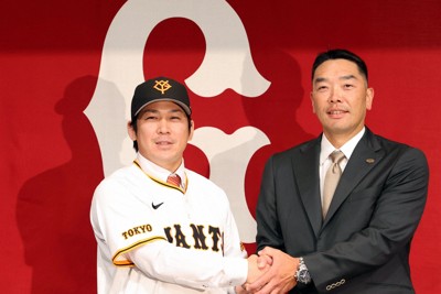 巨人の入団記者会見でユニホームに袖を通し、フォトセッションに臨む甲斐拓也（左）と阿部慎之助監督＝東京都千代田区で2024年12月26日、幾島健太郎撮影