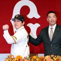 巨人の入団記者会見でユニホームに袖を通し、フォトセッションに臨む甲斐拓也（左）と阿部慎之助監督＝東京都千代田区で2024年12月26日、幾島健太郎撮影