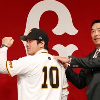 巨人の入団記者会見でユニホームに袖を通し、フォトセッションに臨む甲斐拓也（左）と阿部慎之助監督＝東京都千代田区で2024年12月26日、幾島健太郎撮影