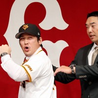 巨人の入団記者会見でユニホームに袖を通し、フォトセッションに臨む甲斐拓也（左）と阿部慎之助監督＝東京都千代田区で2024年12月26日、幾島健太郎撮影