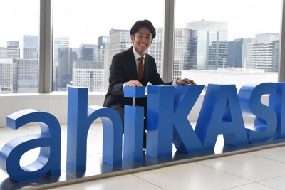 会社のロゴと一緒に笑顔を見せる旭化成の相沢晃選手＝東京都千代田区で2024年11月6日、岩壁峻撮影