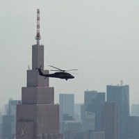 東京都渋谷区の「NTTドコモ代々木ビル」の手前を通過する米陸軍ヘリ「ブラックホーク」。高さ202メートルの都庁北展望室から撮影しており、ヘリの高度はNTTドコモ代々木ビルより確実に低いことが分かる＝2020年8月18日、加藤隆寛撮影（写真は動画から）