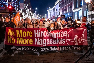 たいまつを掲げ、市街地を歩く被爆者ら。前列右から2人目が佐久間邦彦さん＝ノルウェー・オスロで（原水爆禁止日本協議会/ピースボート提供）