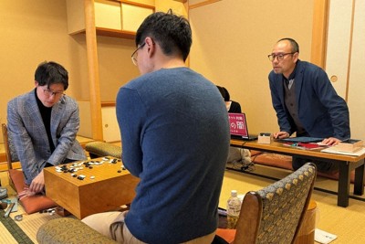 井山裕太王座（左）と洪爽義五段（手前）の対局後の検討を見守る後藤俊午九段（右）＝大阪市北区で2024年12月19日