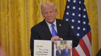 米ホワイトハウスで開かれた日米首脳会談後の共同記者会見で、石破茂首相に贈るメッセージ入りの記念写真を紹介するトランプ米大統領＝ワシントンで2025年2月7日、秋山信一撮影