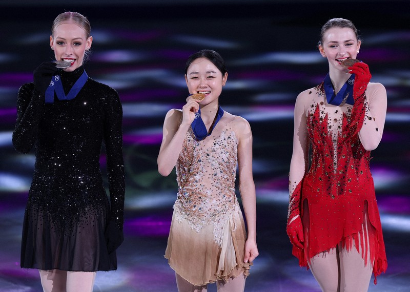 女子の表彰式後の記念撮影でメダルをかむ（左から）2位で米国のブラディー・テネル、1位で韓国の金采衍、3位で米国のサラ・エバーハード＝ソウルで2025年2月23日、猪飼健史撮影