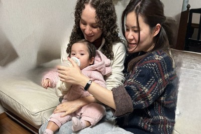 めいのエリーちゃんにミルクをあげる白石佳織さん（右）。左は米国人の義姉＝白石さん提供