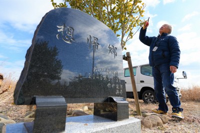 自宅解体時に残したツバキの木を枝切りする赤井俊治さんと、2022年に建てた石碑「想帰郷」＝福島県大熊町小入野で2025年2月10日午前9時37分、尾崎修二撮影