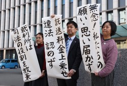 託送料金をめぐる行政訴訟の控訴が棄却され、福岡高裁前で「思い届かず」などと書かれた紙を掲げる弁護士ら＝福岡市中央区で2025年2月26日、金澤稔撮影