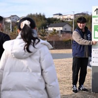 「3・11メモリアルネットワーク」の職員として、東京から来た修学旅行生に「津波避難場所」の看板を説明する阿部任さん。「見かけたら高台はどこか確認して」＝宮城県石巻市で2025年1月27日、北山夏帆撮影