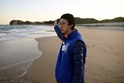 豊間海岸に立つ小野陽洋さん。海岸沿いにあった自宅で津波にのまれるも一命を取り留めた。「たまたま助かった命。意味のある活動に使いたい」＝福島県いわき市で2025年2月15日、北山夏帆撮影