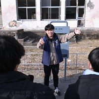 東京から来た修学旅行生に震災遺構になった母校の門脇小学校を案内する阿部任さん。「津波は1階までしかこなかったけれど、3階まで火災が襲った。高台に逃げた子どもたちは全員無事でした」＝宮城県石巻市で2025年1月27日、北山夏帆撮影