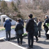 藤沼湖の決壊による犠牲者の慰霊碑に向かって献花する参列者＝福島県須賀川市長沼地区で2025年3月9日、根本太一撮影