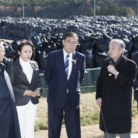 除染土の仮置き場を視察する石破茂首相（左から4人目）と、説明する伊沢史朗・双葉町長（同5人目）。左端は内堀雅雄・福島県知事＝福島県双葉町で2024年12月14日午前11時半（代表撮影）