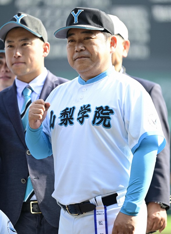 優勝した2023年のセンバツで試合後アルプス席へのあいさつを終え、笑顔で戻る山梨学院の吉田洸二監督（右）と吉田健人部長＝阪神甲子園球場で23年4月1日、平川義之撮影