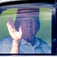 自身が所有するフロリダ州のゴルフ場をあとにするリムジンの中から手を振るトランプ大統領＝15日、ウェストパームビーチ（AP＝共同）