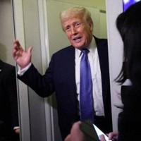 　16日、専用機「エアフォースワン」の中で報道陣に話すトランプ米大統領（ロイター＝共同）