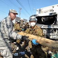 自衛隊員と力を合わせ、小学校の校庭に残るがれきの撤去作業をする米兵（左）＝宮城県石巻市で2011年4月1日、小林努撮影