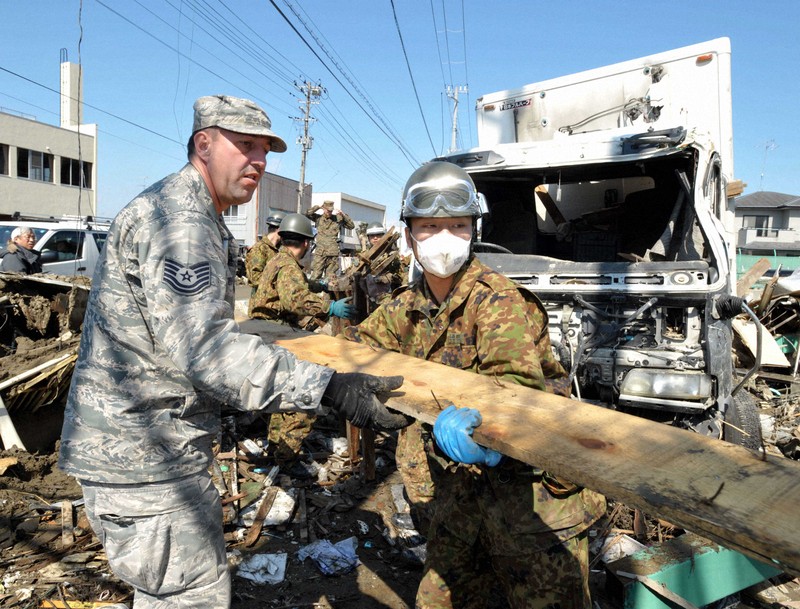 自衛隊員と力を合わせ、小学校の校庭に残るがれきの撤去作業をする米兵（左）＝宮城県石巻市で2011年4月1日、小林努撮影