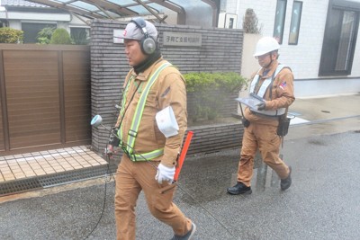 人工衛星の調査結果をタブレットで確認しながら、聴診器のような道具で地中の音を聞く点検作業員＝兵庫県尼崎市で2025年3月5日、露木陽介撮影