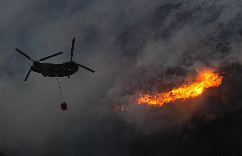 激しく燃え上がる山林火災現場で消火活動に当たる陸上自衛隊のヘリ＝岡山市南区と玉野市の境界付近で2025年3月25日午後6時6分、本社ヘリから