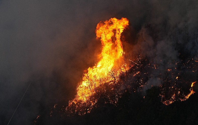 道路のそばで激しく燃える山林火災現場＝岡山市南区と玉野市の境界付近で2025年3月25日午後6時8分、本社ヘリから