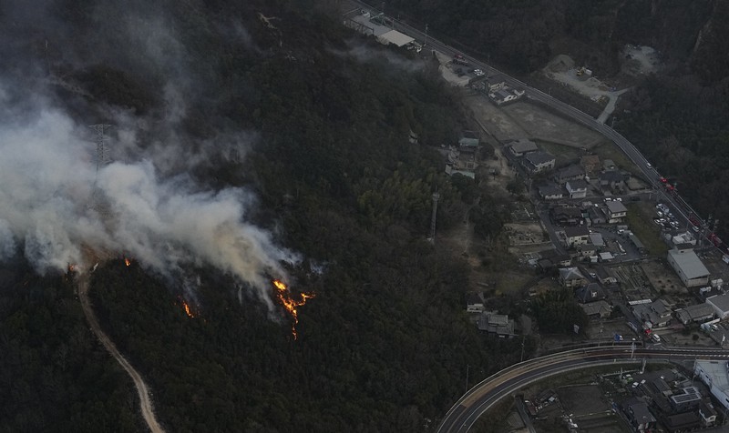住宅地近くで燃える山林火災の現場＝岡山市南区で2025年3月25日午後6時、本社ヘリから