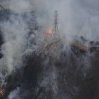 山林火災の火と煙に包まれる鉄塔＝岡山市南区で2025年3月25日午後6時、本社ヘリから