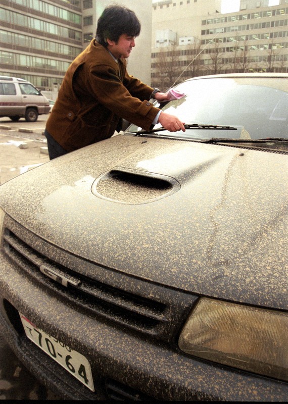 黄砂飛来が多かった2002年、札幌市内の駐車場で車に降った黄砂を掃除する市民＝札幌市中央区で2002年3月22日、橋本政明撮影