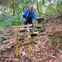 石井神社がかつてあったとされる場所に立つ鳥居とほこらを案内する磯部友記雄さん＝出雲崎町井鼻で2025年3月2日午後2時15分、中津川甫撮影