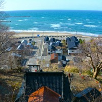 現在の石井神社（中央下）の上にある良寛記念館からは、遠くの海面にうっすらと浮かぶ佐渡島が見られる＝出雲崎町米田で2025年3月14日午後3時19分、中津川甫撮影