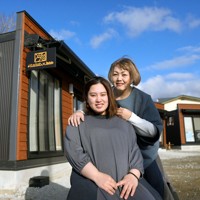 「katak×bee」の前で笑顔を見せる母親の関根真紀さん（奥）と娘の摩耶さん。摩耶さんは妊娠中で4月に第1子を出産予定だ＝北海道平取町で2025年3月2日、貝塚太一撮影