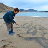 砂鉄とみられる黒い砂がまだらに広がる海辺＝出雲崎町久田で2025年3月2日午後0時22分、中津川甫撮影