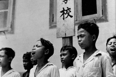 愛国行進曲を歌う学童＝インドネシアのボルネオ島バリクパパンで海軍報道班員・山本撮影。1943年3月10日、大阪本社にネガ到着