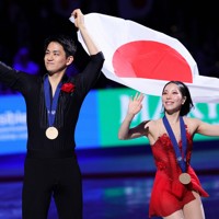 優勝し、メダルを胸に笑顔で手を振る三浦璃来選手、木原龍一選手組＝米ボストンで2025年3月27日、吉田航太撮影