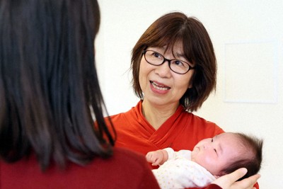孫を抱っこしながら、娘（左）と一緒に家族の思い出を振り返る松島理恵さん＝東京都板橋区で2025年2月13日、幾島健太郎撮影