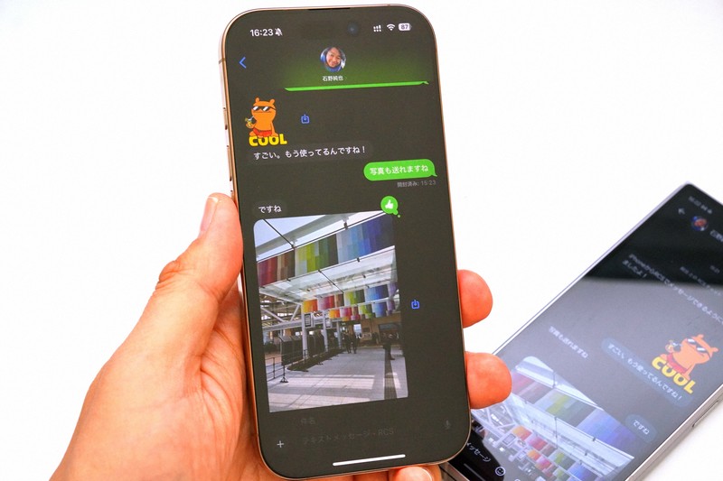 KDDIがiPhoneのRCSに対応（写真手前）。標準搭載の「メッセージ」アプリでAndroidスマホ（写真奥）にも写真や動画、スタンプなどを送れるようになった＝筆者撮影
