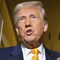 大統領専用機（エアフォースワン）の機内で記者たちの取材に応じるトランプ米大統領＝2025年4月12日、AP