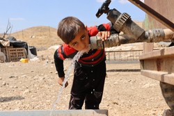 給水車の蛇口からじかに水を飲むパレスチナの少年＝パレスチナ自治区ヨルダン川西岸バルダラ村近郊で2024年5月30日、金子淳撮影