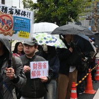 雨が降る中、財務省前に並び「解体」を訴えるデモ参加者＝東京都千代田区で2025年4月13日午後1時39分、川口峻撮影
