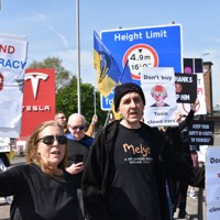 米電気自動車大手テスラの販売店前で「テスラを買うな」「トランプ、マスクを止めろ」などと書かれたボードを掲げるデモ参加者＝ロンドンで2025年4月12日、福永方人撮影